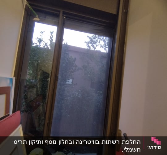 חלון עם תריסים פתוחים חלקית ומסגרת מתכת
